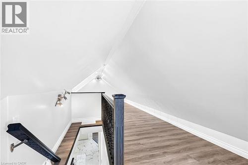 Upper-level landing with wood-finish flooring, recessed lighting, track lighting, and a dark wood newel post - 4 Albemarle Street, Hamilton, ON 