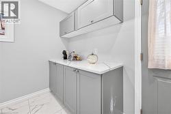 Built-in cabinetry with light gray finish, white countertop, and tile flooring with a marble-effect pattern - 