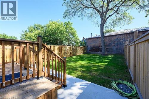 Expansive backyard featuring a wood-plank deck, concrete patio, and a manicured lawn - 4 Albemarle Street, Hamilton, ON 