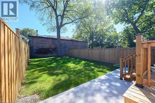 Expansive backyard featuring a manicured lawn, concrete patio, and a wood deck with stairs - 4 Albemarle Street, Hamilton, ON 