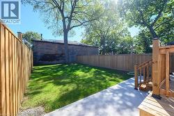 Expansive backyard featuring a manicured lawn, concrete patio, and a wood deck with stairs - 