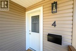 Entry door with decorative glass insert, metal wall-mounted mailbox, and exterior wall lantern - 