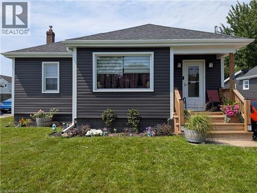 Dark gray horizontal siding exterior with white trim, dark shingle roof, and a wood front porch - 487 Scholfield Avenue N, Welland, ON 