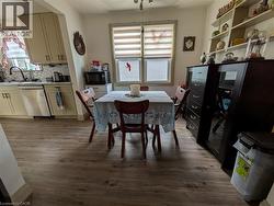 Kitchen area featuring wood-finish flooring, light-toned cabinetry, a stainless steel dishwasher, and a patterned tile backsplash - 