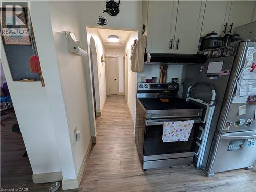 Kitchen featuring stainless steel range, stainless steel refrigerator, and cream cabinetry with dark hardware - 487 Scholfield Avenue N, Welland, ON 