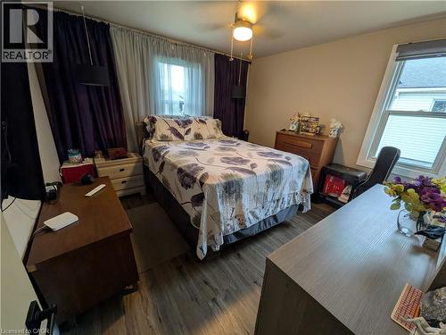 Wood-finish flooring throughout, multiple windows with blinds, and a ceiling fan with integrated lighting - 487 Scholfield Avenue N, Welland, ON 