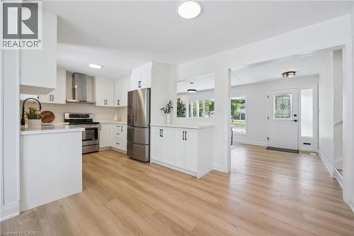 Modern kitchen featuring white cabinetry, stainless steel appliances, a tile backsplash, and light wood-finish flooring - 299 Dale Crescent, Waterloo, ON 