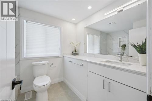 Contemporary bathroom featuring a white vanity with an integrated sink, polished chrome faucet, and expansive wall-mounted mirror - 299 Dale Crescent, Waterloo, ON 