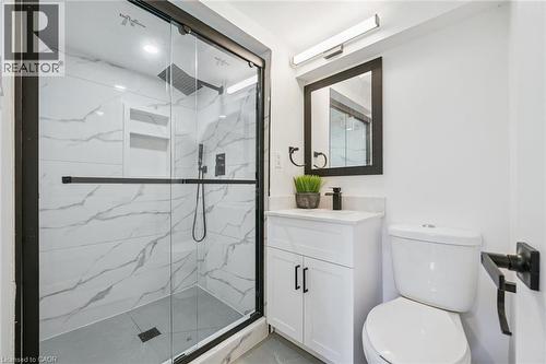 Contemporary bathroom featuring a spacious shower with black-framed glass enclosure, white marble-patterned tile, and two inset shelves - 299 Dale Crescent, Waterloo, ON 