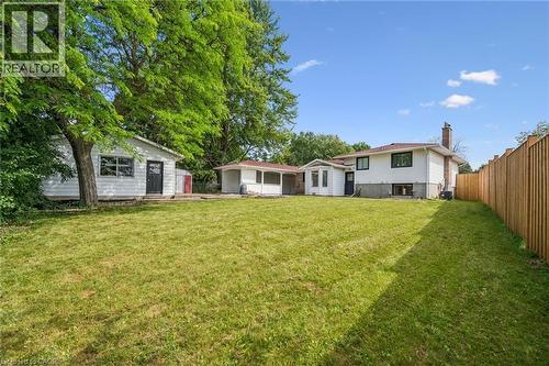 Spacious backyard featuring a large grassy area, a privacy fence, and multiple outbuildings - 299 Dale Crescent, Waterloo, ON 