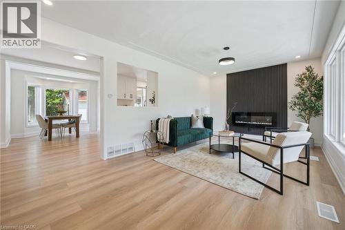Living area featuring light wood-finish flooring, recessed ceiling lighting, and a modern fireplace with a black slatted accent wall - 299 Dale Crescent, Waterloo, ON 