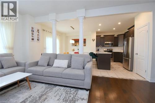 Open-concept living space featuring wood-finish flooring, recessed lighting, white walls, and a kitchen with dark cabinetry and stainless steel appliances - 25 Guest Street, Hamilton, ON 