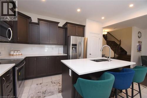 Contemporary kitchen featuring dark wood cabinetry, stainless steel appliances, a center island with sink, white countertops, and recessed lighting - 25 Guest Street, Hamilton, ON 
