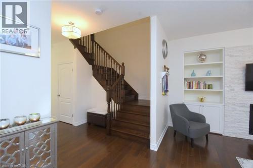 Wood-finish flooring throughout, featuring a dark wood staircase with spindle railings - 25 Guest Street, Hamilton, ON 