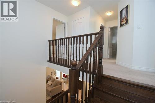 Wood-finish staircase with dark banister, light-colored wall paint, and recessed ceiling lighting - 25 Guest Street, Hamilton, ON 