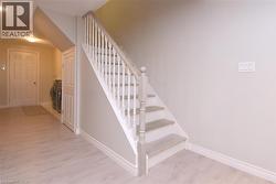 Staircase with painted risers and wood-finish treads, light-toned wood-finish flooring, and a paneled interior door - 