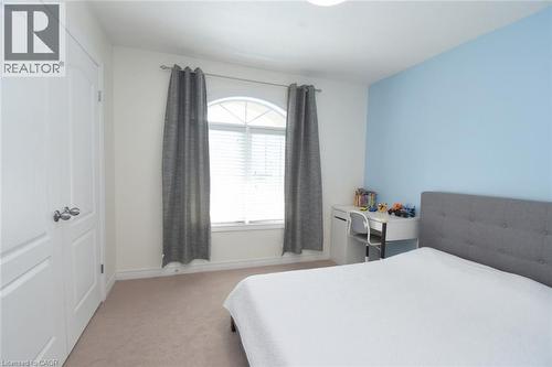 Arched window with blinds, light-toned carpeting, and a light blue accent wall - 25 Guest Street, Hamilton, ON 