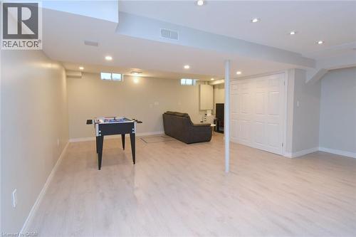 Spacious finished lower level with light wood-finish flooring, recessed lighting, and white bi-fold closet doors - 25 Guest Street, Hamilton, ON 