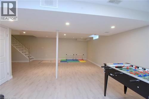 Expansive finished lower level featuring recessed lighting, wood-finish flooring, and a white painted staircase - 25 Guest Street, Hamilton, ON 
