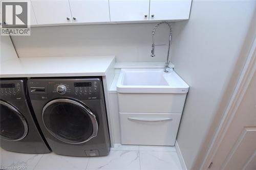 White upper cabinetry, white countertops, built-in utility sink with a flexible chrome faucet, and white floor tiling - 25 Guest Street, Hamilton, ON 