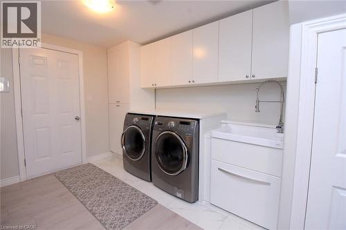 White upper cabinetry, tall storage cabinet, and utility sink with a gooseneck faucet - 25 Guest Street, Hamilton, ON 