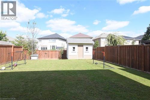 Expansive grassy yard with wood panel fencing, featuring a detached storage shed with shingle roofing - 25 Guest Street, Hamilton, ON 