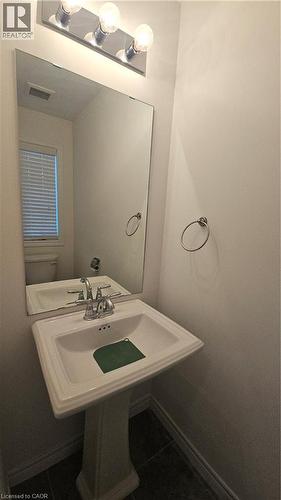 Pedestal sink with chrome faucet, large wall-mounted mirror, and vanity lighting - 3 Sharp Drive, Ancaster, ON 