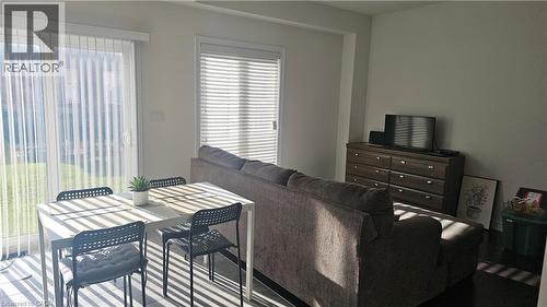White walls, dark wood-finish flooring, sliding glass door with vertical blinds, window with horizontal blinds - 3 Sharp Drive, Ancaster, ON 