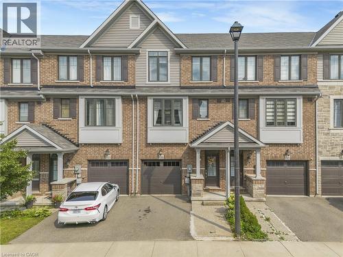 Brick and siding exterior with a covered porch entry, single-car garage, and upper-level windows with shutters - 1890 Rymal Road E Unit# 144, Hamilton, ON 
