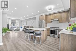 Open-concept living space featuring wood-finish flooring, recessed lighting, and a kitchen island with seating - 