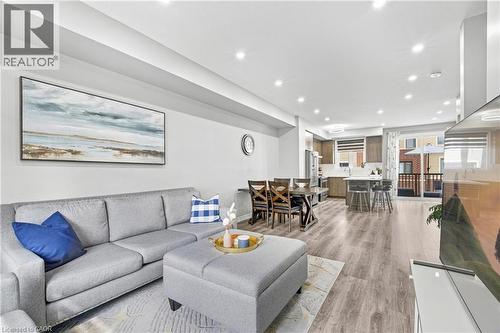 Open-concept living area featuring wood-finish flooring, recessed lighting, a modern kitchen with a center island, and a balcony - 1890 Rymal Road E Unit# 144, Hamilton, ON 