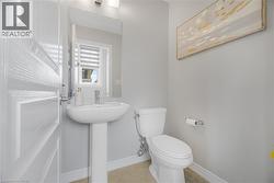 Pedestal sink with chrome faucet, wall-mounted mirror, overhead vanity lighting, and a window with blinds - 