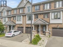 Brick exterior with gabled roofline, multiple windows with dark shutters, covered entry, and attached garage - 