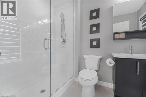 Glass-enclosed shower with white subway tile, chrome shower fixture, single vanity with dark cabinetry, integrated sink, and wall-mounted mirror - 1890 Rymal Road E Unit# 144, Hamilton, ON 