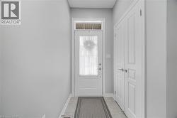 Entryway featuring a panel door with transom window, tile flooring, and double bi-fold panel doors - 