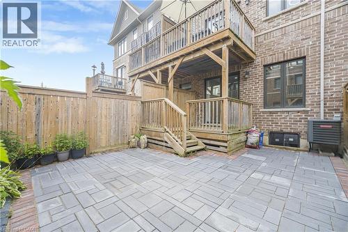 Paved patio area, wooden privacy fencing, multistory wooden deck, brick exterior, and multiple large windows - 1890 Rymal Road E Unit# 144, Hamilton, ON 