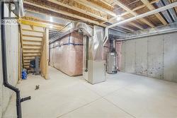 Unfinished basement with concrete flooring, exposed wood joists, and utility access - 