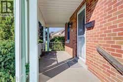 Brick exterior with covered porch, concrete flooring, and decorative metal railings - 