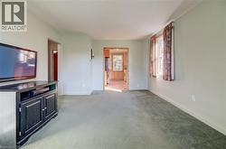 Carpeted flooring throughout, light-toned walls, and a window with curtains - 