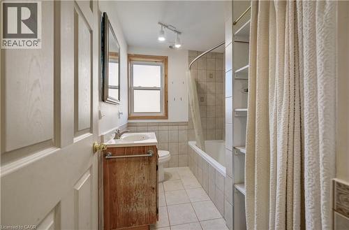 Bathroom featuring a single vanity with an integrated sink, bathtub, built-in shelving, and a window - 174 Bridgeport Road E, Waterloo, ON 
