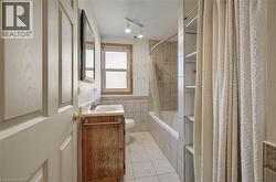 Bathroom featuring a single vanity with an integrated sink, bathtub, built-in shelving, and a window - 