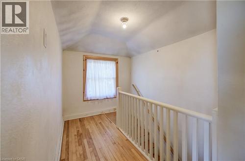 Wood-finish flooring with a white railing and a window with wood trim, hallway upper level - 174 Bridgeport Road E, Waterloo, ON 