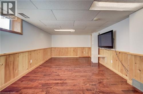 Room featuring wood-finish flooring, half-wall wood paneling, a drop ceiling with recessed lighting, and a window - 174 Bridgeport Road E, Waterloo, ON 