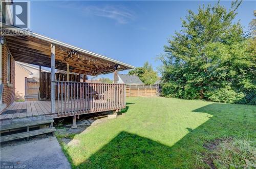 Expansive backyard featuring a covered wood deck, wood privacy fencing, and mature trees - 174 Bridgeport Road E, Waterloo, ON 
