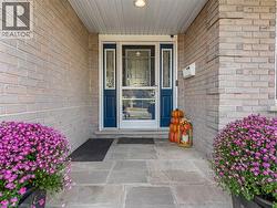 Brick facade with a stone entry, featuring a blue front door with glass sidelights and an overhead soffit - 