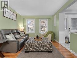 Inviting living room showcasing soft sage-green walls, hardwood flooring, and abundant natural light from dual French doors - 