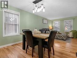 Wood-finish flooring, multiple windows with vertical blinds, modern chandelier, and light green wall paint - 