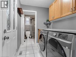 Laundry area featuring upper wood cabinetry, counter space, and tile flooring - 