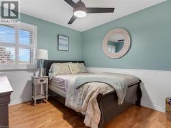 Light wood-finish flooring, white beadboard wainscoting, and a ceiling fan with integrated lighting - 