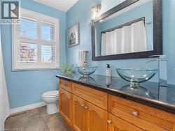 Dual glass vessel sinks with modern chrome faucets, rich wood-finish vanity with ample storage, black countertop, large framed mirror, and window with white plantation shutters - 